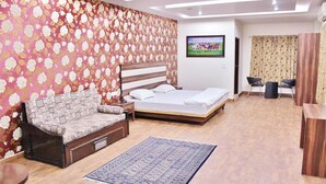 Un dormitorio con cama, sofá, televisor y escritorio con sillas.