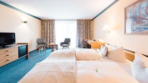 Hotellihuone, jossa on suuri sänky, työpöytä, tuoli, televisio ja taulu seinällä.