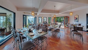 Uma sala de jantar espaçosa com pé direito alto, janelas amplas e mobiliário moderno.