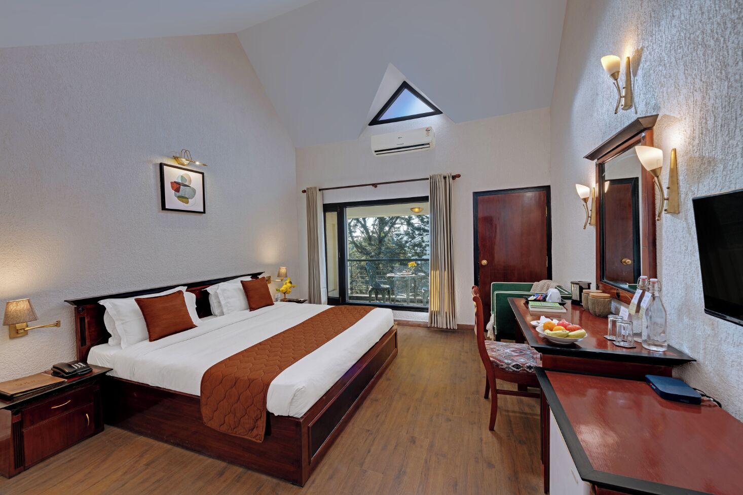 A hotel room with a large bed, a desk with a chair, a mirror, and a window with curtains.