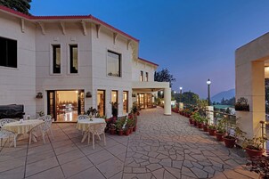 Un hotel con patio amoblado, plantas en macetas y vistas a las montañas.