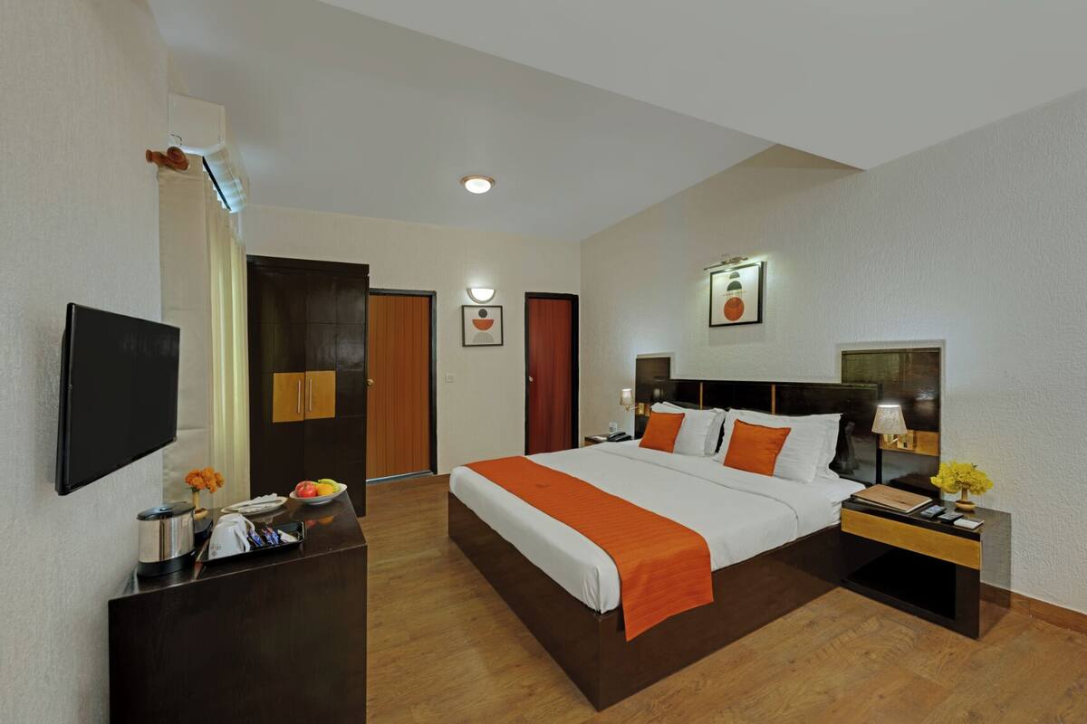 Habitación de hotel con cama, mesita de noche, televisor, armario y aire acondicionado de pared.