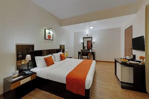 A hotel room with a large bed, a desk with a chair, a television, and a mirror. - 8fold-Pinecrest By LaRiSa, Bhimtal (Nainital)