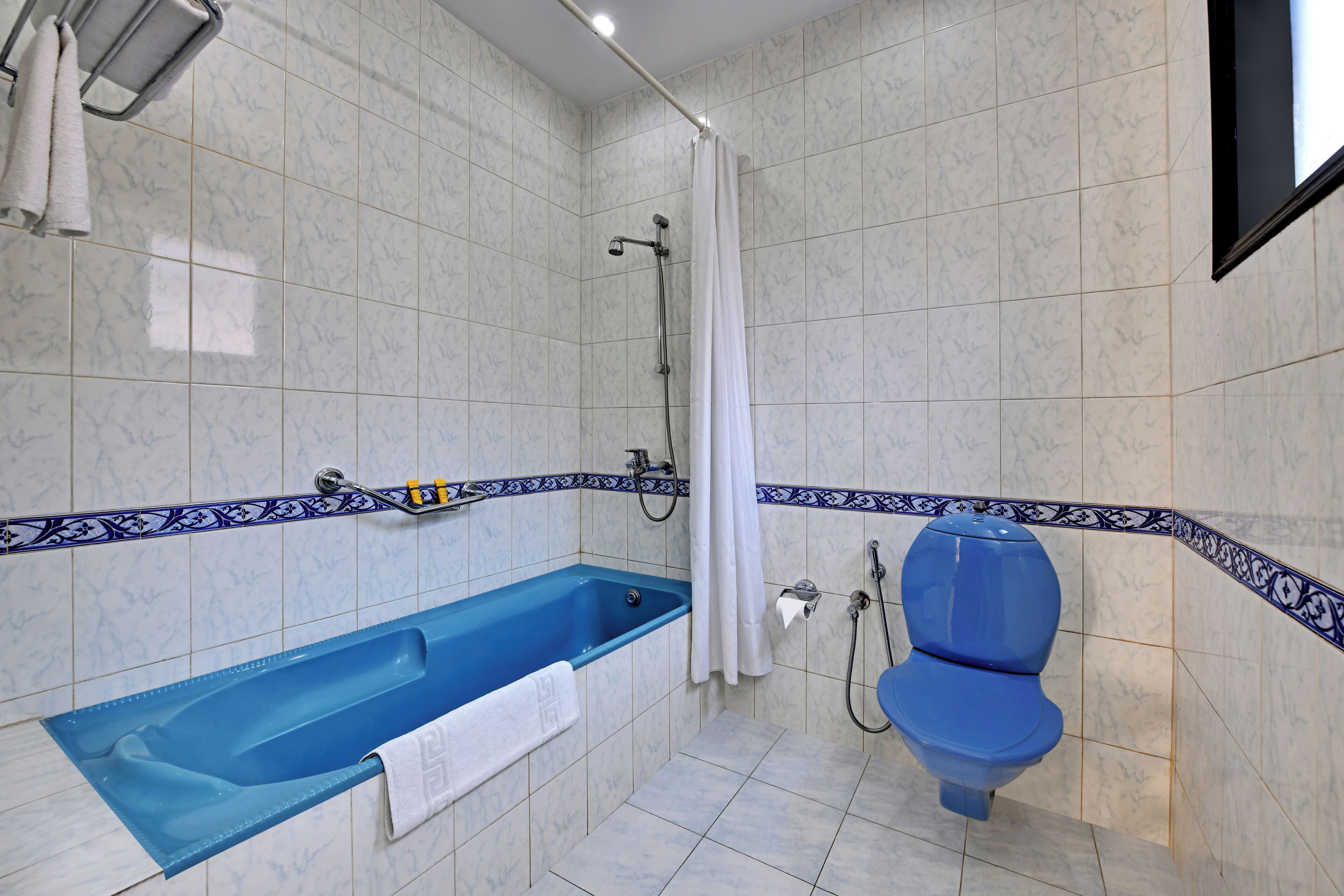 A bathroom with a bathtub, toilet, shower, and a towel rack.