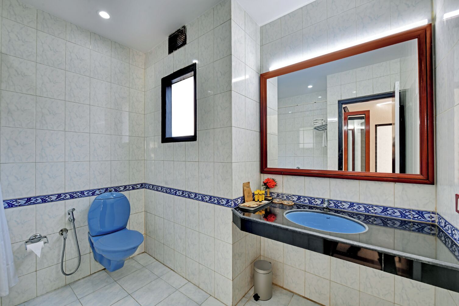 A bathroom with a blue toilet, a sink, and a mirror.