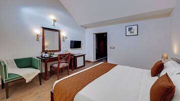 Habitación de hotel con cama, escritorio, silla, televisor y puerta.