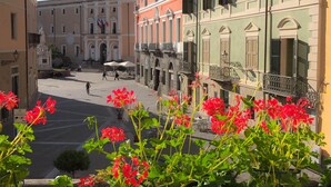 Une vue de rue avec des bâtiments, un ciel dégagé et des fleurs rouges au premier plan.