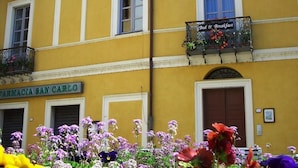 Un bâtiment jaune avec une enseigne indiquant « Chambres d’hôtes » et « Pharmacie San Carlo ».