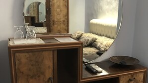 Une coiffeuse en bois avec un grand miroir, un petit meuble de rangement et une table de chevet.