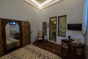 Una camera da letto con un letto, una sedia, una scrivania, un televisore e una libreria.
