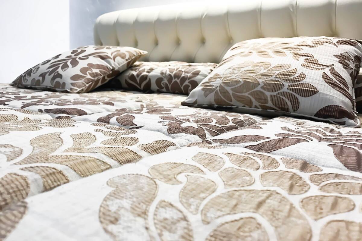 Una cama con colcha estampada y almohadas a juego.