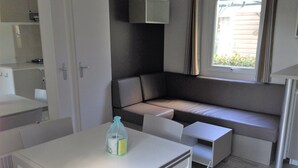 Un espacio habitable pequeño con una mesa de comedor, un sofá y una ventana.