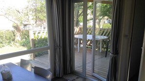 Una habitación con una puerta corrediza de vidrio que da a una terraza exterior con una mesa y sillas.