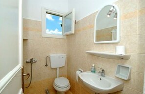 A small bathroom with a toilet, sink, and a window. - Asante Paros (Paros)