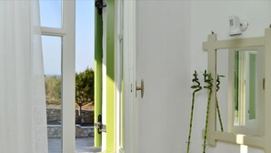 A bathroom with a window, a mirror, and two clear glass vases with green plants. - Asante Paros (Paros)