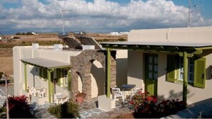 A coastal building with a stone archway, outdoor seating, and a view of the sea. - Asante Paros (Paros)