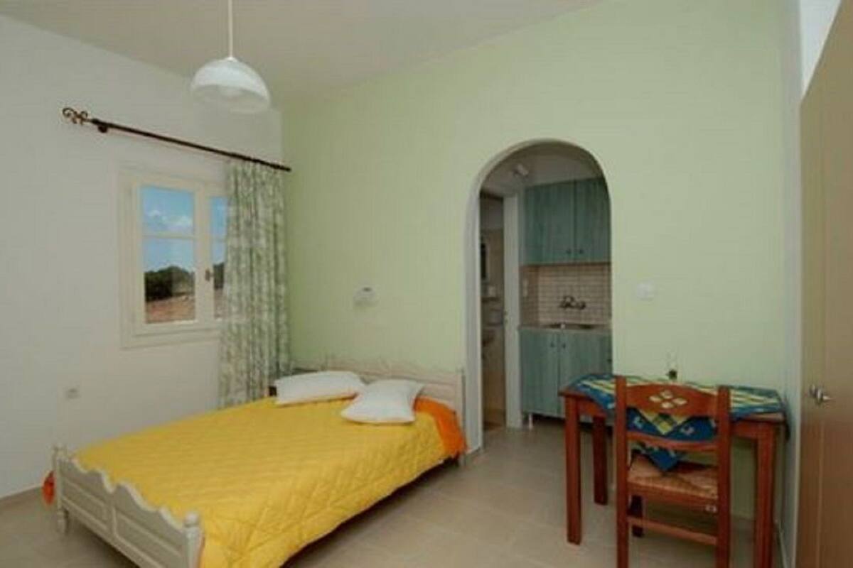 A bedroom with a bed, a desk, and a window.