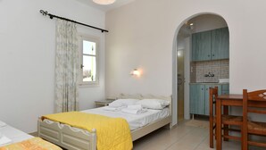 A bedroom with a bed, a bedside table, a chair, and a window with curtains. - Asante Paros (Paros)