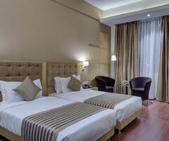 Una habitación de hotel con dos camas, un cabecero grande, una silla y una lámpara.