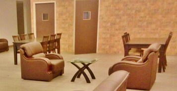 Un vestíbulo de hotel con sofás de cuero, una mesa de centro de vidrio y sillas de madera.