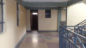 A corridor with a tiled floor, a blue railing, and a door at the end. - Mau Summit Hotel (Narok)