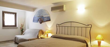 A bedroom with two beds, a wall-mounted air conditioner, and a decorative ship painting.