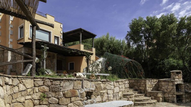 A stone wall with a stone bench and steps leading to a stone structure.