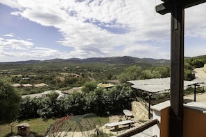 A view of a rural landscape with scattered houses, a clear sky, and distant mountains.