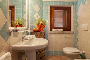 A bathroom with a sink, toilet, and a mirror. There are decorative baskets and a flower arrangement on the counter.