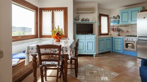 A kitchen with blue cabinets, a dining table with chairs, a TV, and a refrigerator.