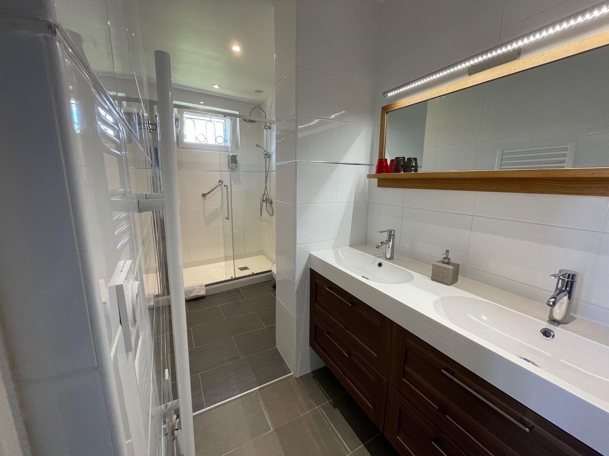 Een moderne badkamer met een douchecabine van glas, een wastafel met spiegel en een wasbak.