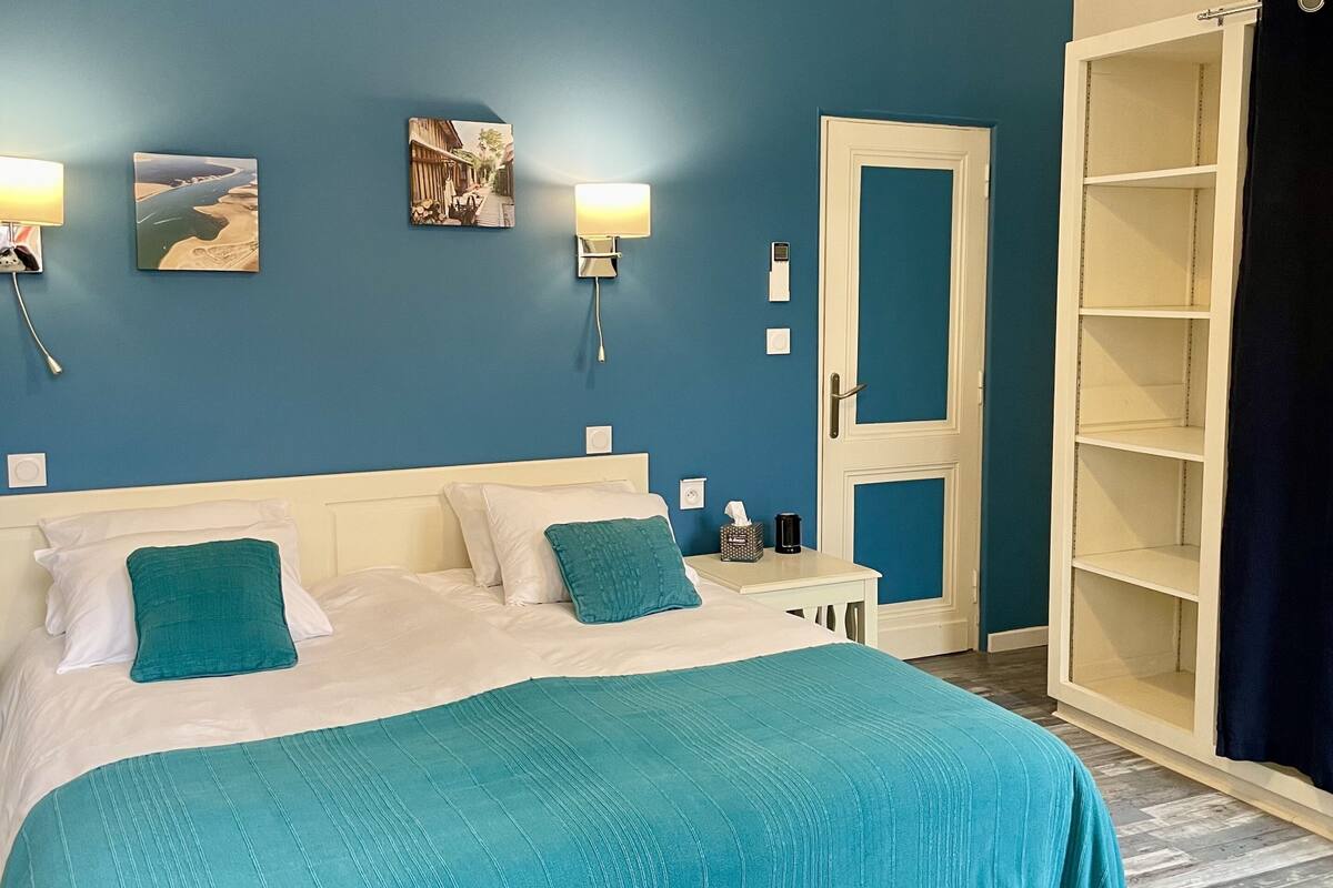 Un dormitorio con una cama, dos lámparas de pared, una mesita de noche y una puerta que da a un armario.