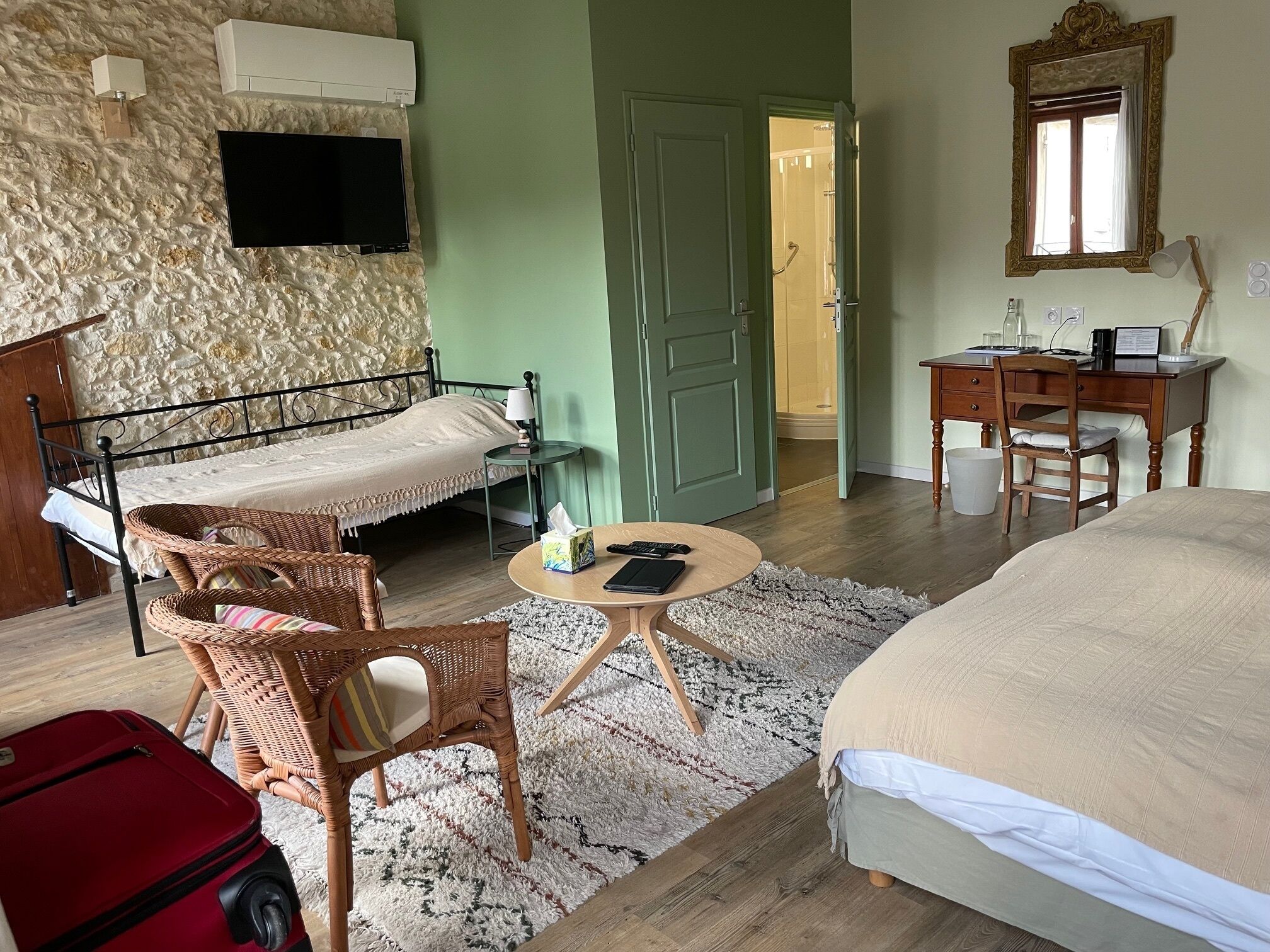 Une chambre à coucher avec un lit, un bureau, une chaise, une télévision et une valise.