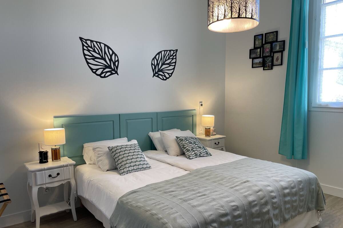 Un dormitorio ordenado con una cama, dos mesitas de noche, una lámpara y una lámpara de pared.