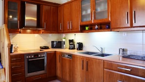 A modern kitchen with wooden cabinets, stainless steel appliances, and a double sink. - Viva Elafonisi (Kissamos)