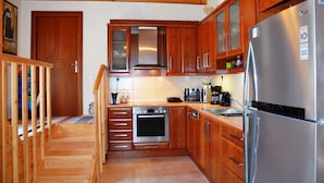 A kitchen with wooden cabinets, a stainless steel refrigerator, a built-in oven, and a microwave. - Viva Elafonisi (Kissamos)