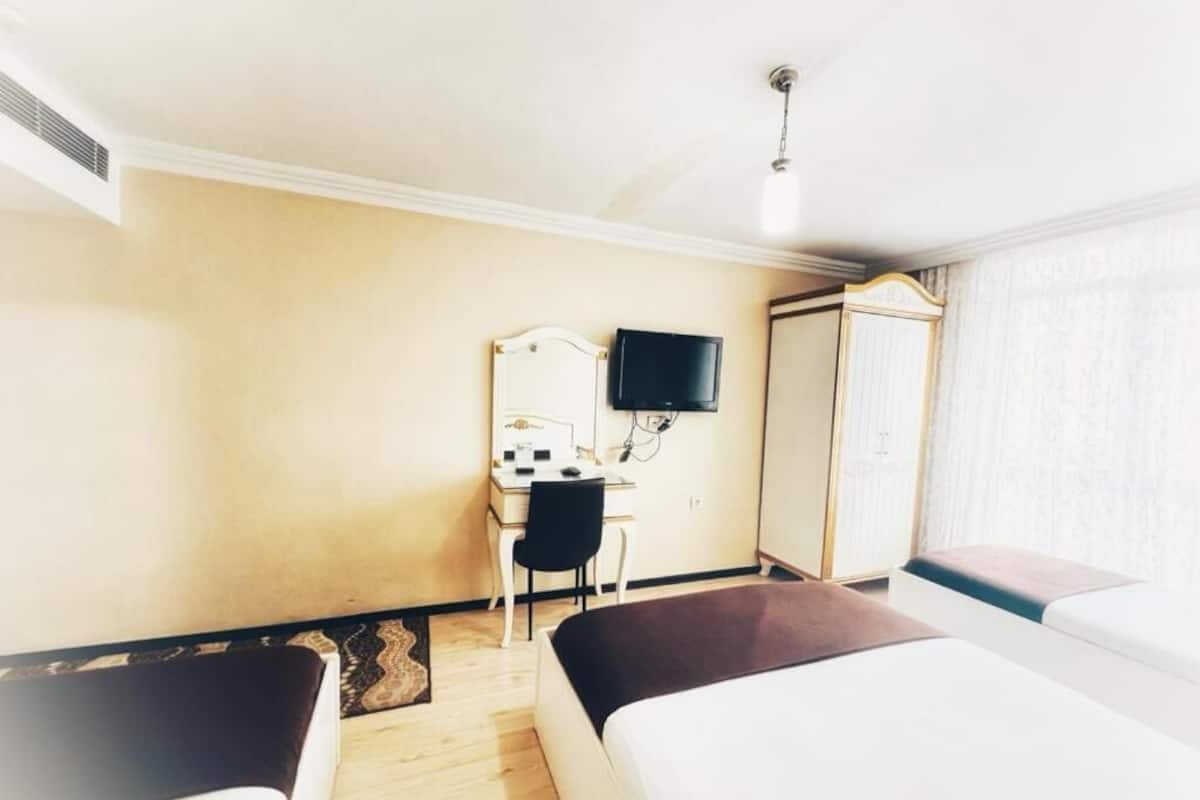A hotel room with two beds, a desk with a chair, a television, and a wardrobe.