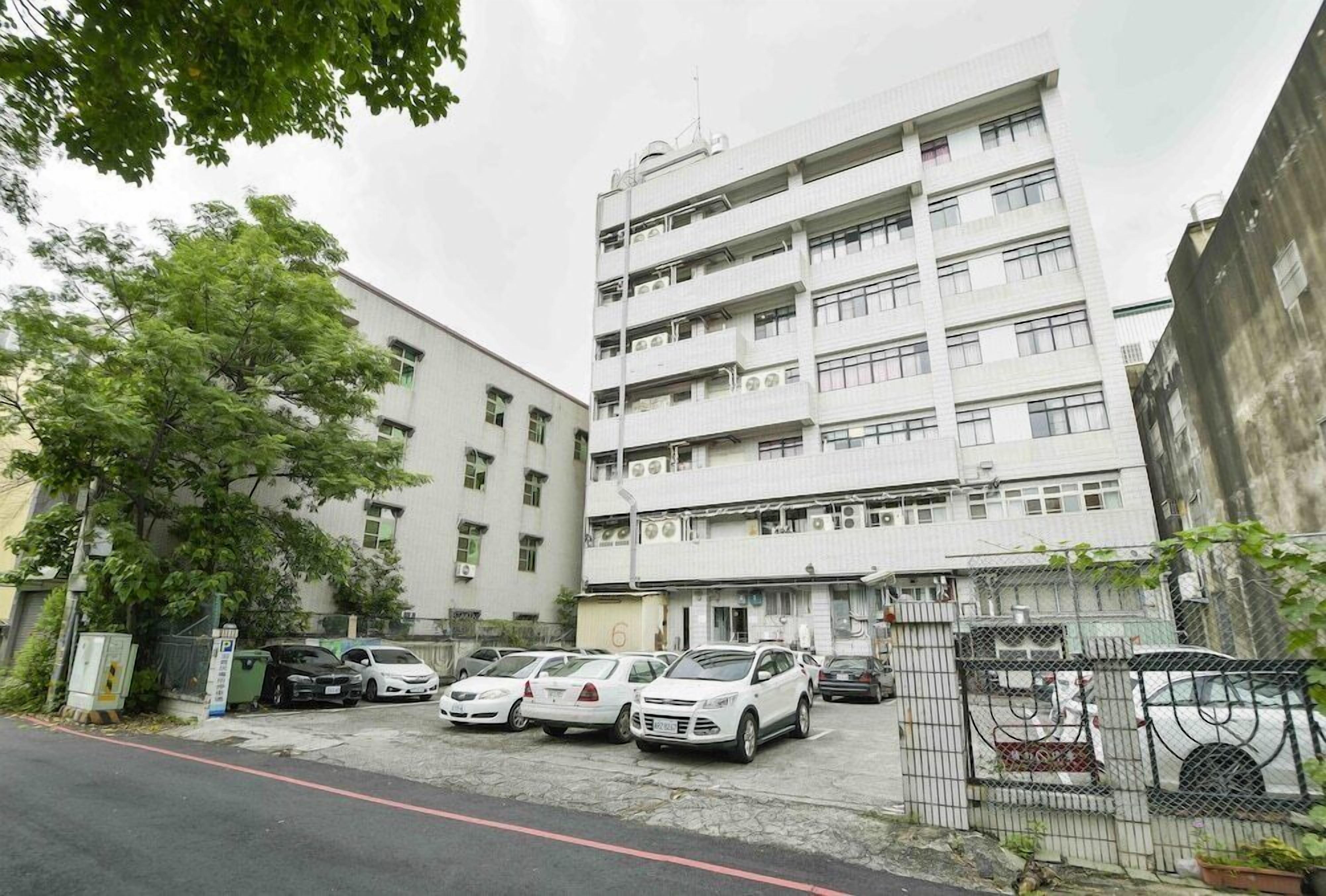 Un edificio residencial de varios pisos con un estacionamiento enfrente.