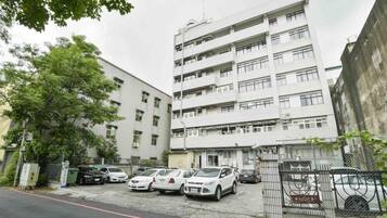 Un edificio residencial de varios pisos con un estacionamiento enfrente.