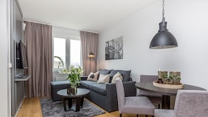 Una sala de estar moderna con un sofá gris, una mesa de centro y un comedor con una mesa redonda y sillas grises.