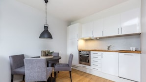 Una cocina moderna con armarios blancos, encimera de madera y un comedor con sillas grises y una mesa.