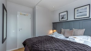 Un dormitorio con una cama, una puerta y dos cuadros en la pared.