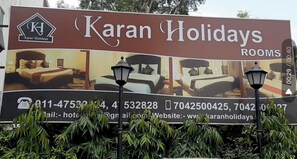 Een reclamebord voor Karan Holidays met contactgegevens en een afbeelding van een slaapkamer.