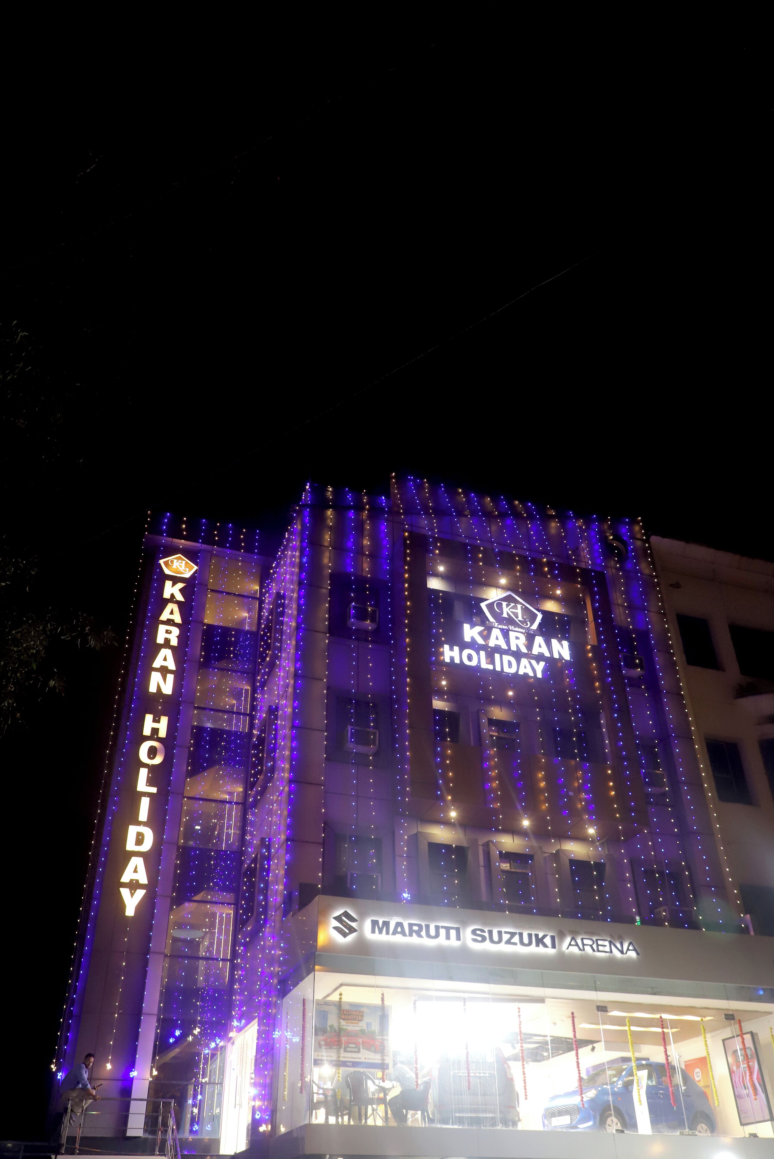 A building with "KARAN HOLIDAY" signage and "MARUTI SUZUKI ARENA" below it.