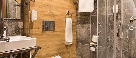 A modern bathroom with a wooden vanity, a toilet, a glass-enclosed shower, and a mirror.