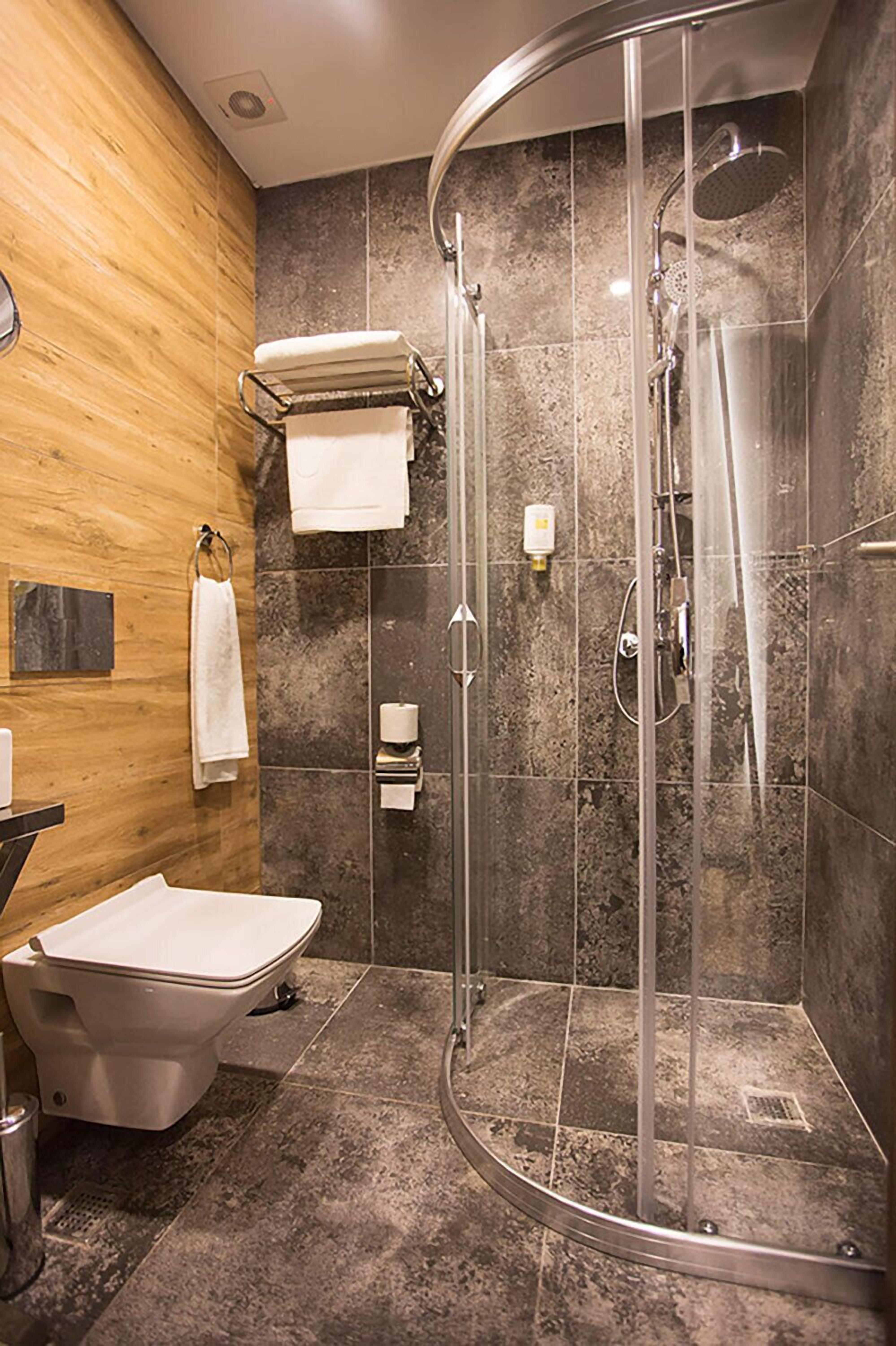 Un baño moderno con ducha de vidrio, inodoro y barra para toallas.