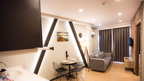 A modern living room with a sofa, a dining table with chairs, and a kitchen area with a sink and countertop. - Long Stay Istanbul (Istanbul)