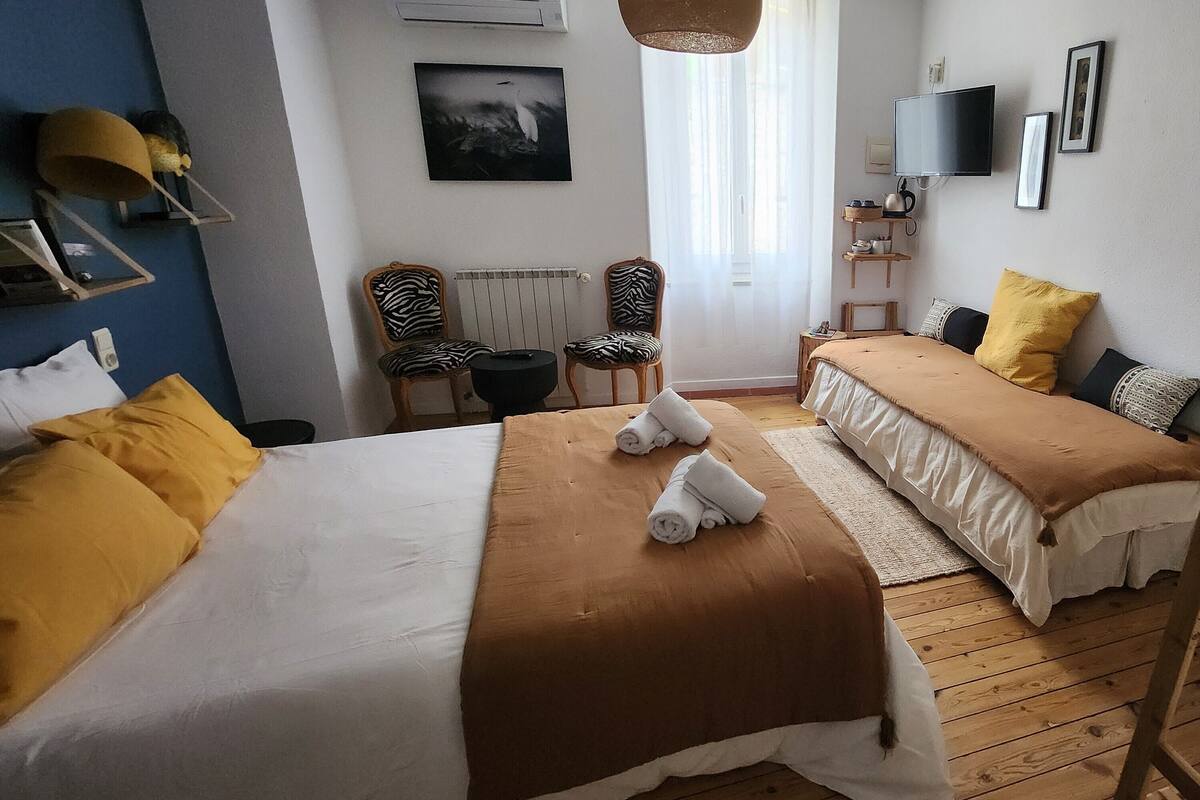 A hotel room with two beds, a sitting area with chairs, a television, and a window with curtains.