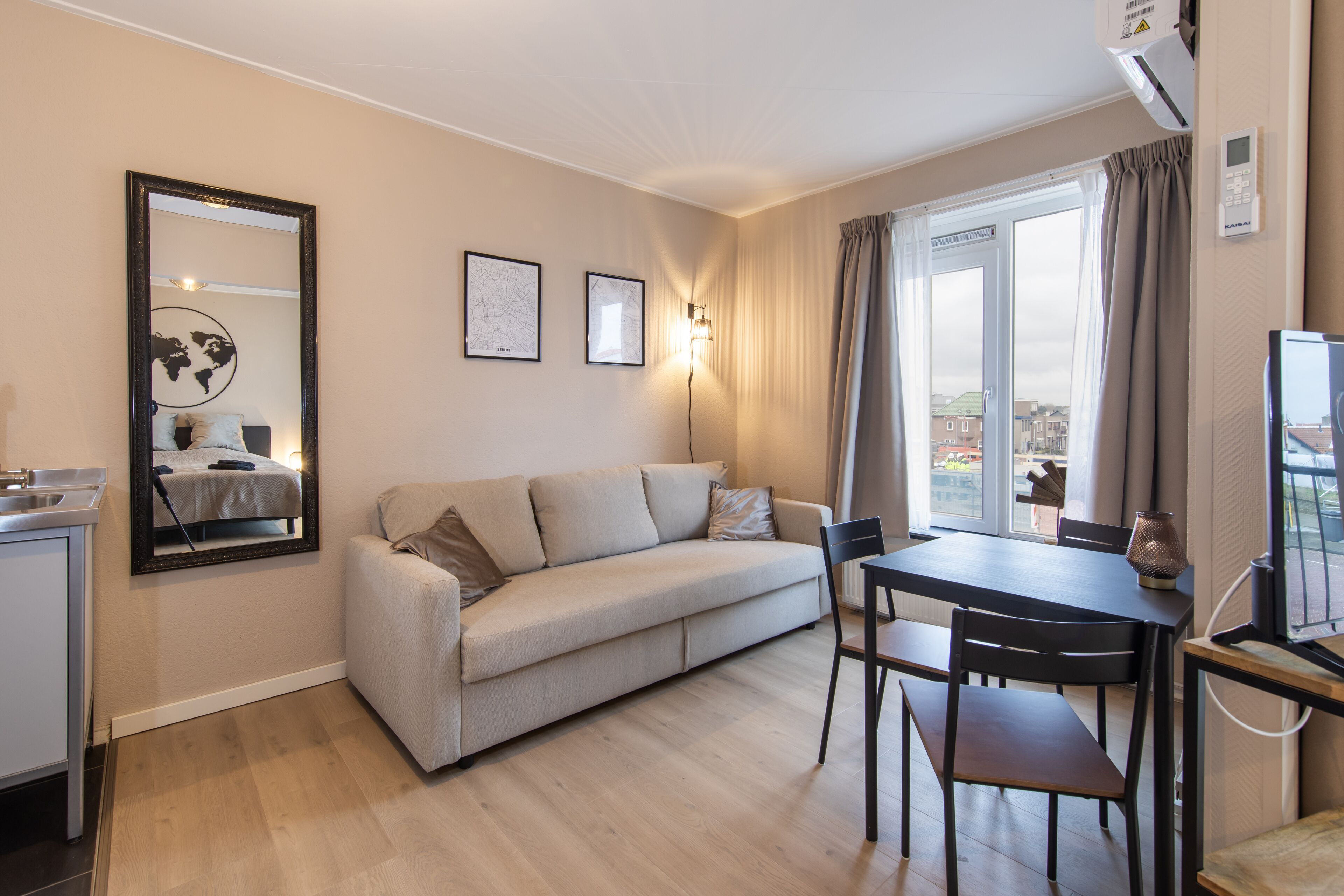 A modern living room with a sofa, dining table, chairs, and a TV.