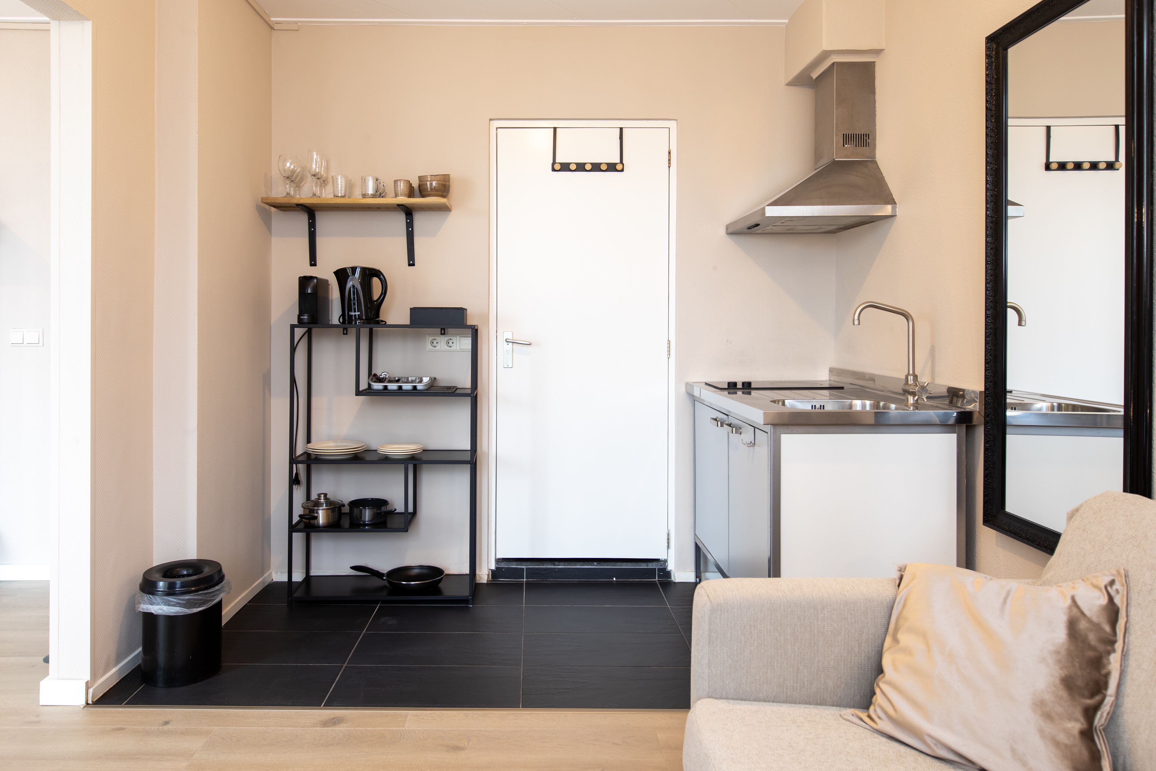 A compact kitchen with a sink, stove, and shelves.